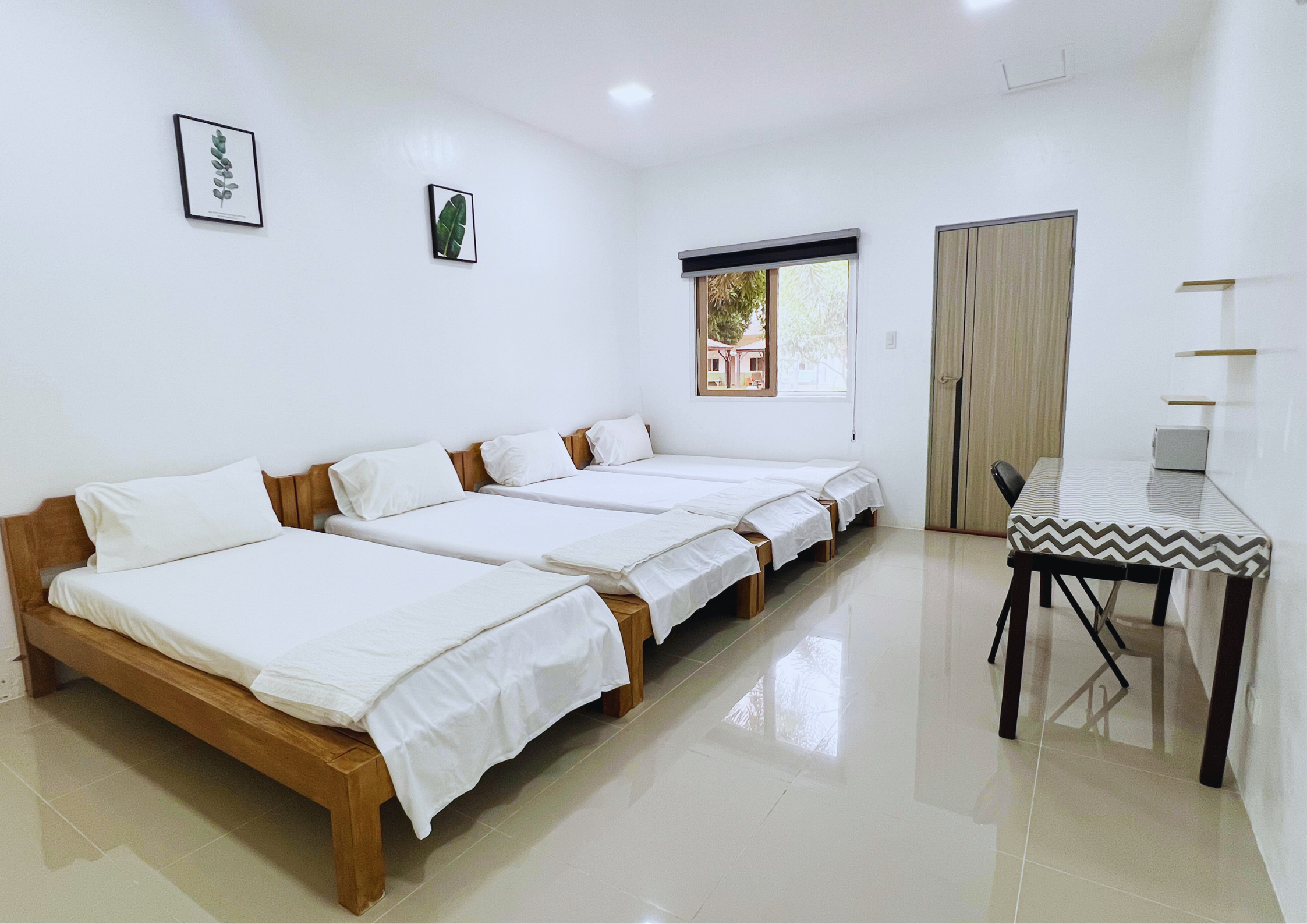 Quadruple Room - Dormitory room standard for four person. it has one bed and a huge cabinet. It has a long table with chairs for studying and a bathroom. It is well lit with a big window.