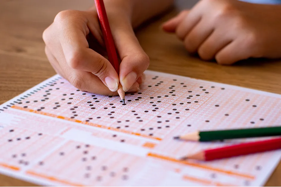 toefl | ielts | pte - hand on paper shading the answers on a scantron sheet.